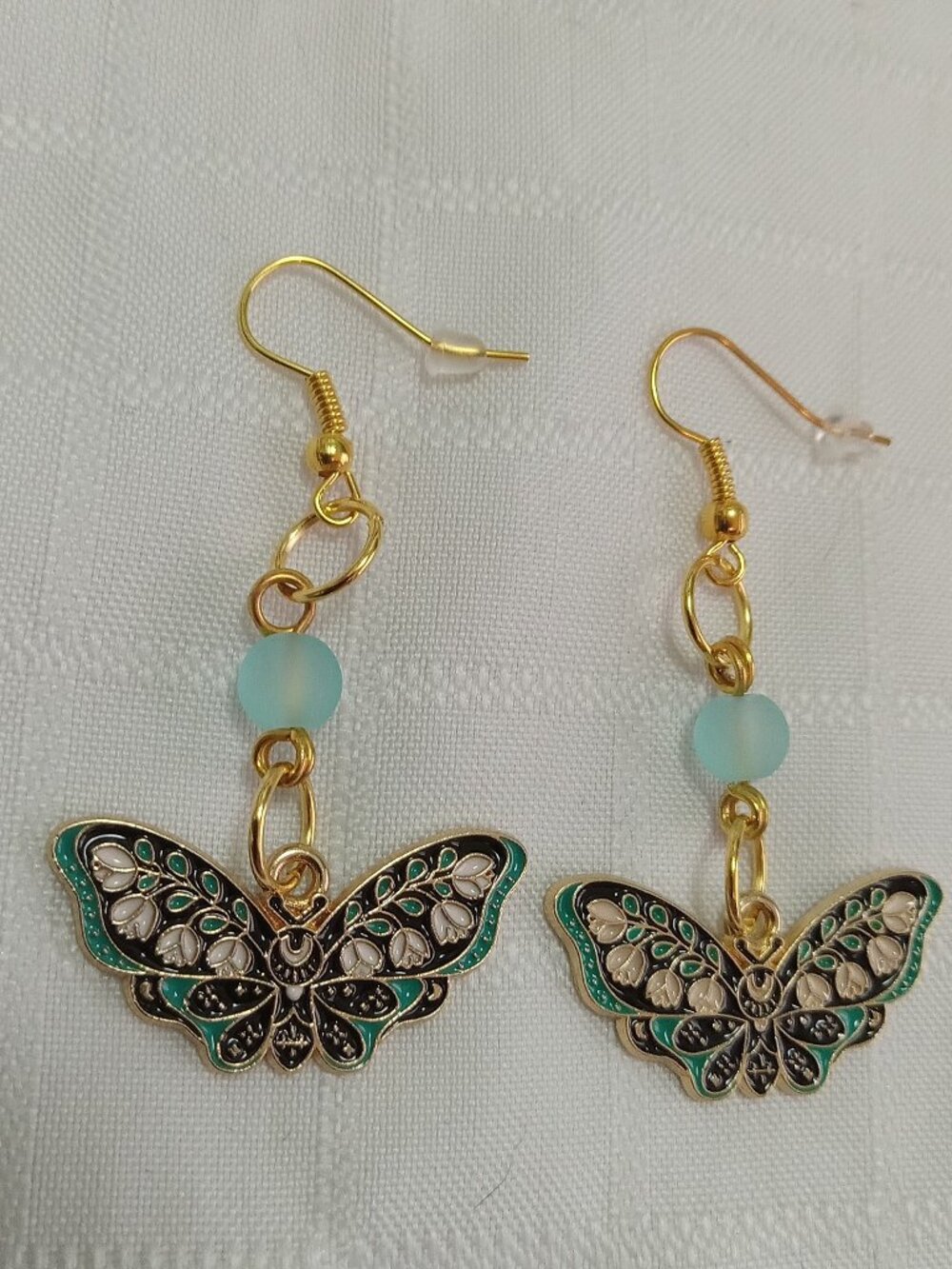 Handmade gold-colored earrings with multicolored enameled butterflies and beads